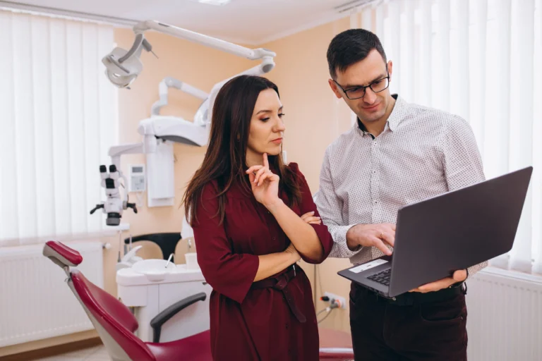 Dentist reviewing information on a laptop with a patient in a dental office